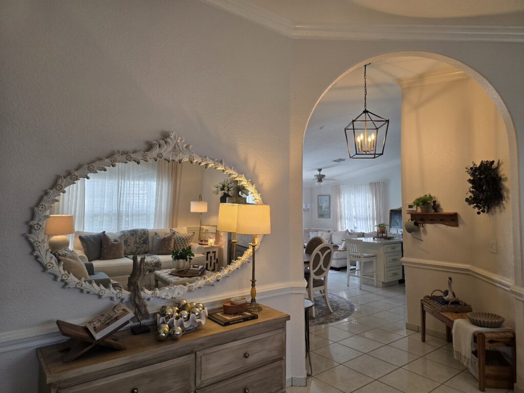 Entryway with an arched opening, carved mirror, wood console table, and warm ambient lighting.