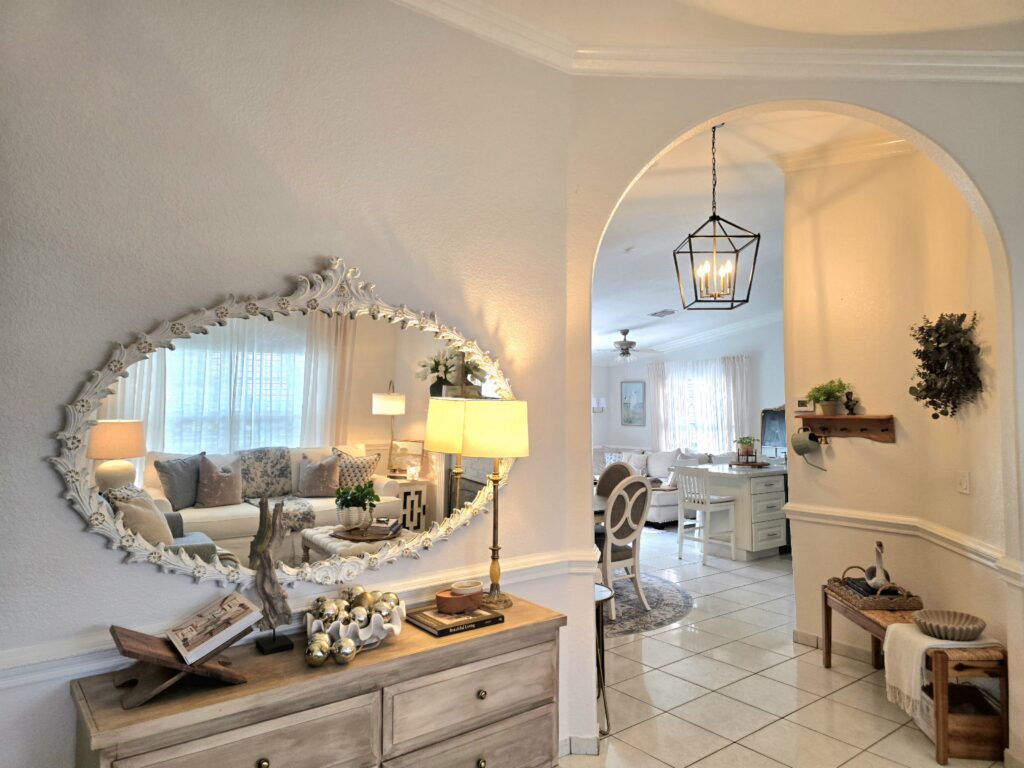 Entryway with an arched opening, carved mirror, wood console table, and warm ambient lighting.