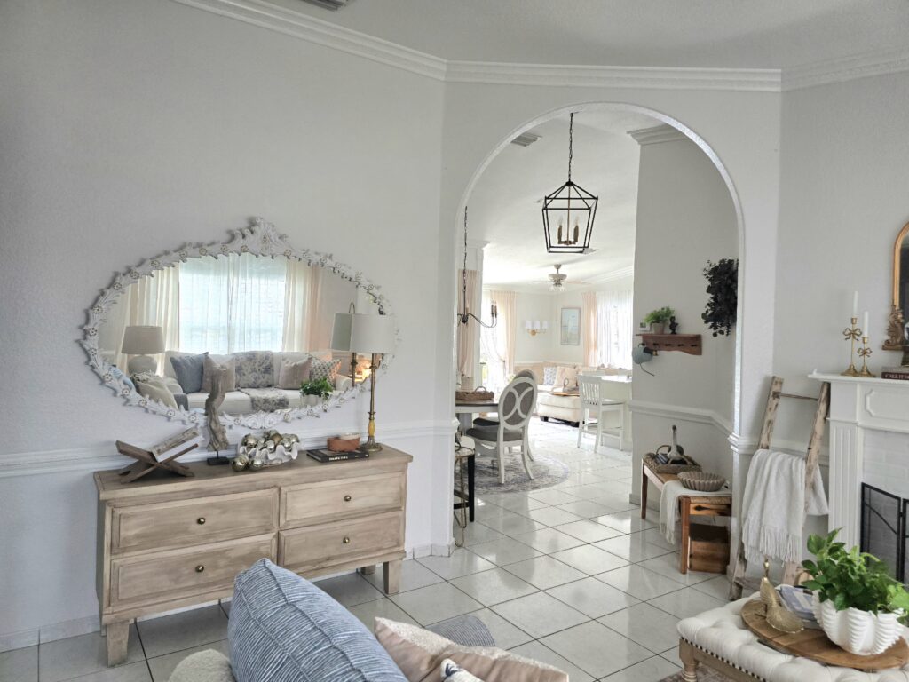 Soft Traditional living room featuring an arched opening, carved mirror, wood console table, and layered neutral décor.