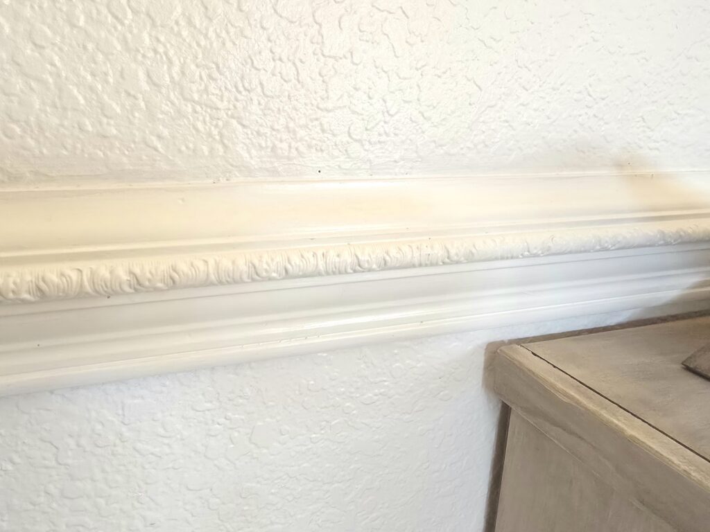 Traditional chair rail molding installed over knockdown wall texture in natural lighting.