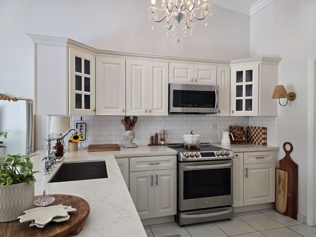 White traditional kitchen with brass hardware, wood accents and crystal chandelier.