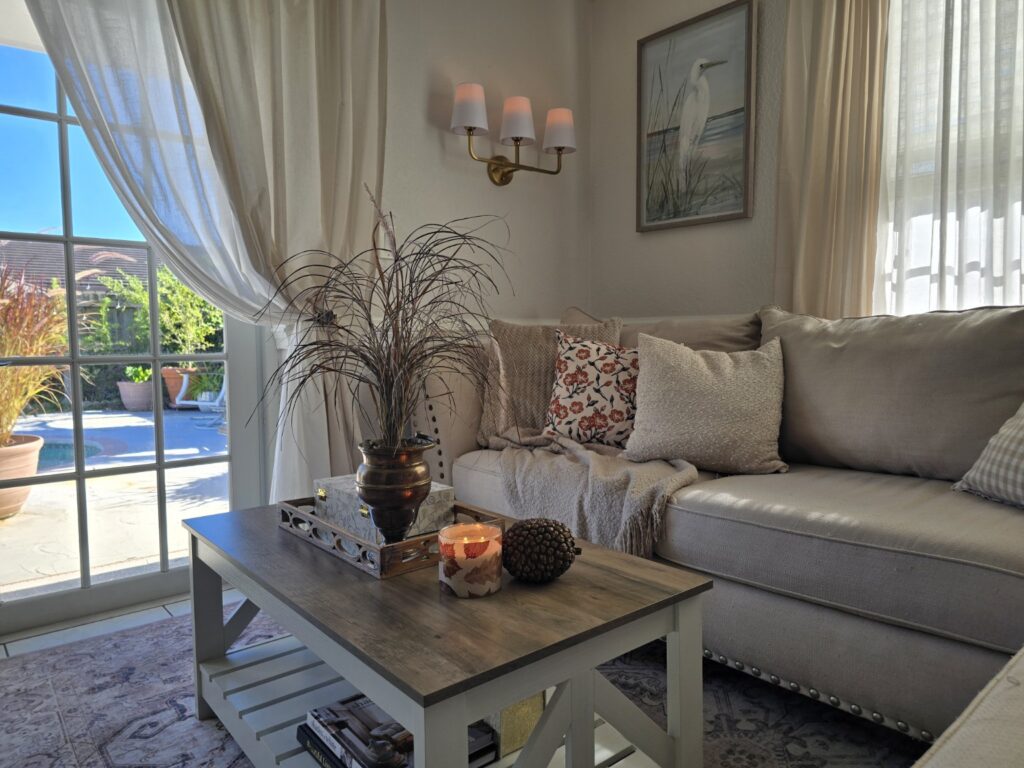 Neutral living room styled for early fall with layered pillows, a soft throw and simple seasonal accents