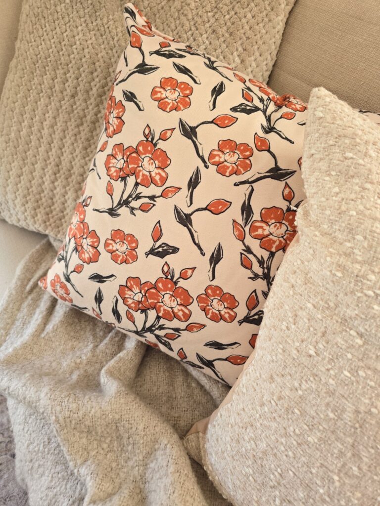 Cream textured pillows and a soft knit throw layered with a rust floral accent pillow