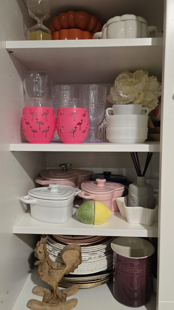 pen pantry shelves holding seasonal decor, colorful glassware, dishes, and serving pieces.