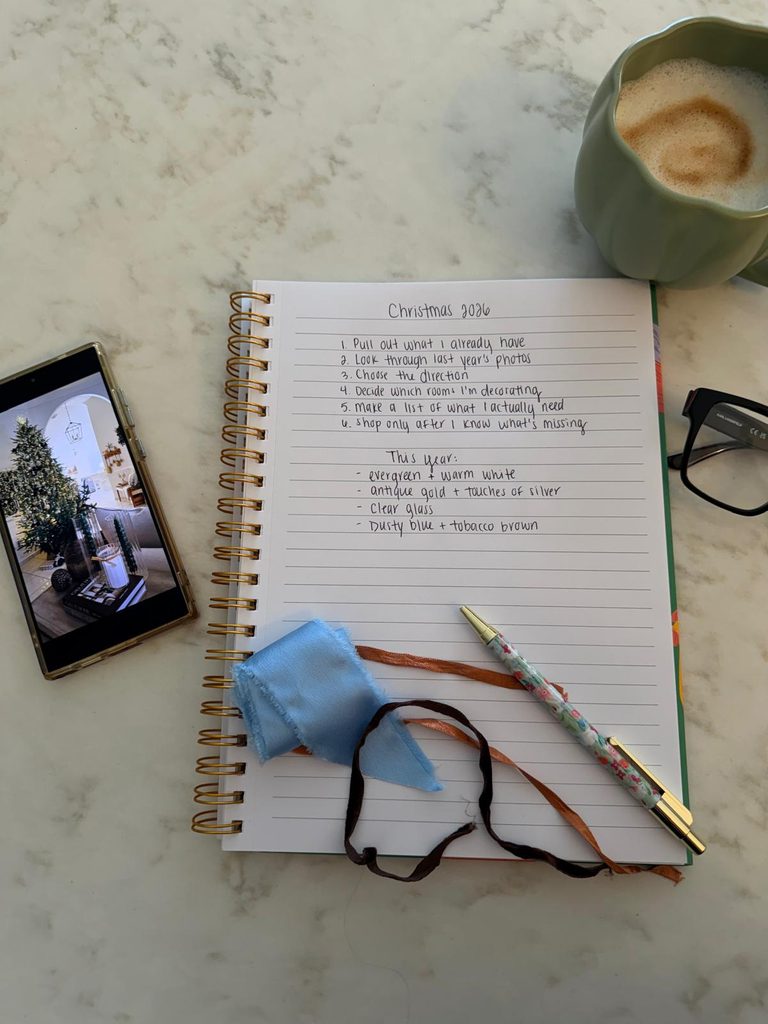 Christmas 2026 decorating plan beside coffee, ribbon samples and a phone showing last year's Christmas tree.