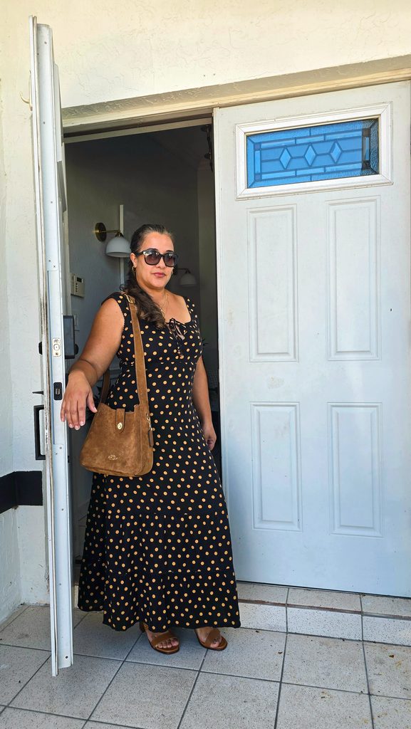 lack polka-dot maxi dress styled with a brown suede bag and sandals for fall in Miami.