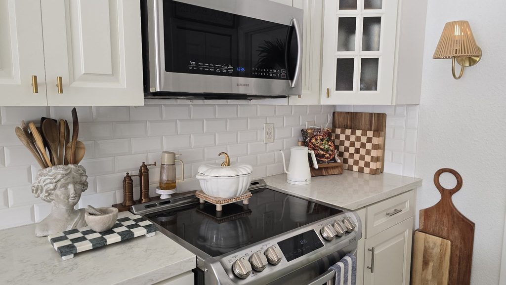 A newer kitchen, kept from feeling like a showroom by the old-feeling pieces — the bust, the wood boards, the copper. Not one era, and that's the point.