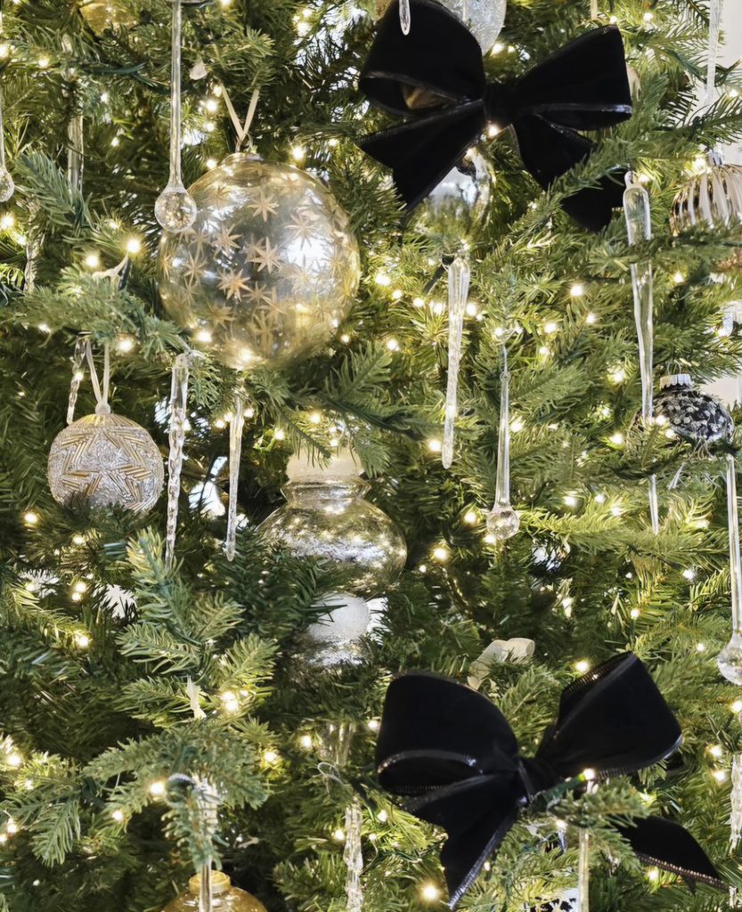 Structured black velvet bow used as a decorative accent among Christmas tree ornaments