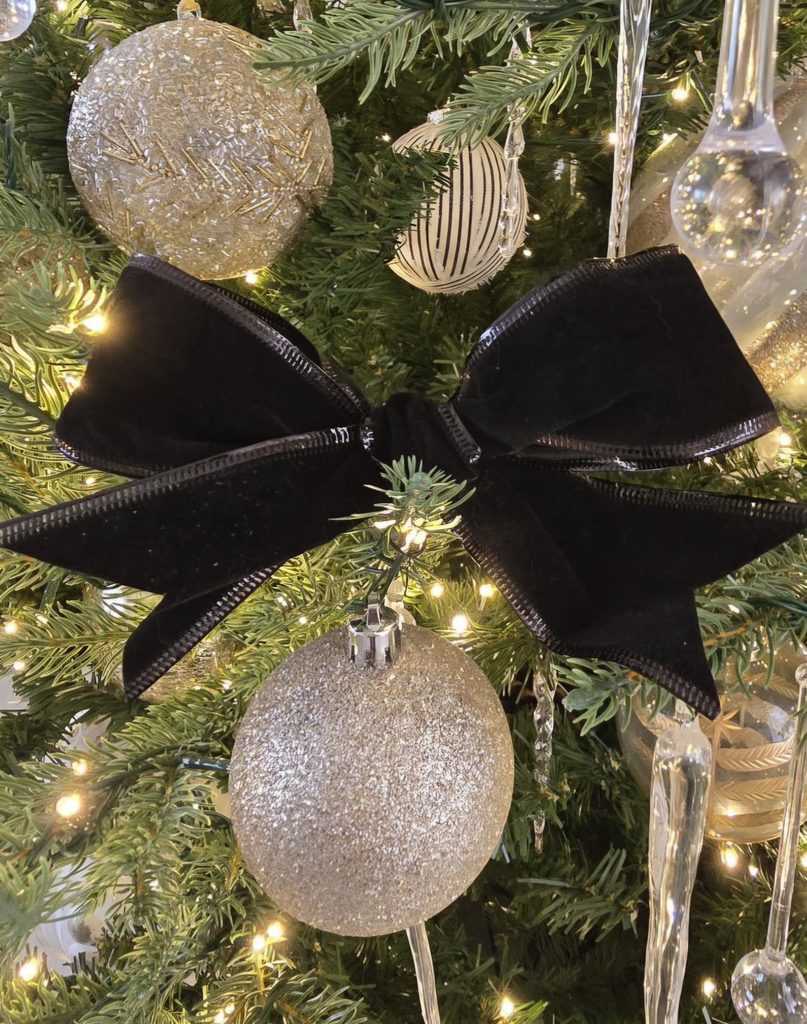 Structured black velvet bow used as a decorative accent among Christmas tree ornaments
