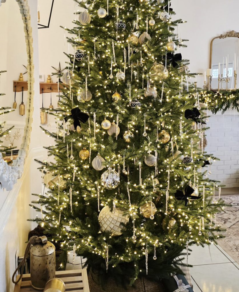 Finished Christmas tree with black velvet bows, warm lights, and gold and silver ornaments