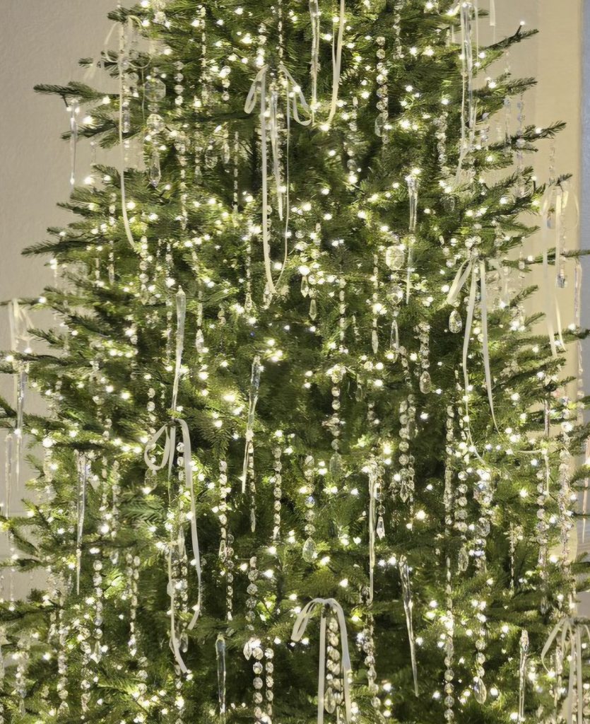 Christmas tree decorated with thin white ribbon bows, crystal garlands, and icicle ornaments