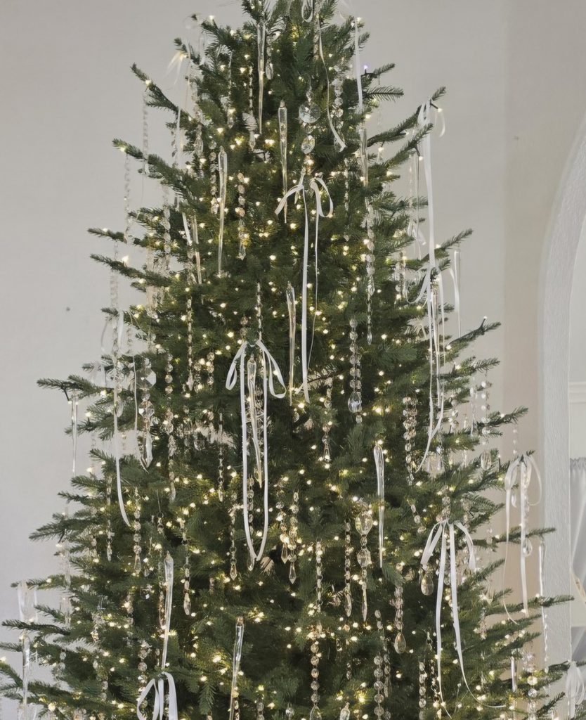 Christmas tree decorated with thin white ribbon bows, crystal garlands, and icicle ornaments